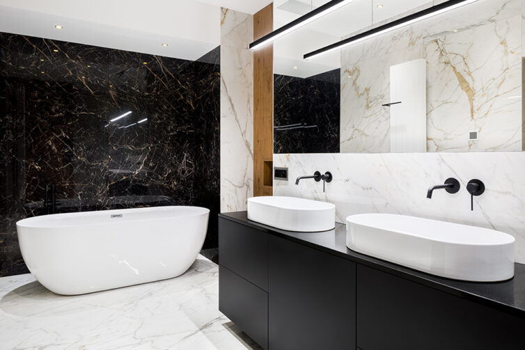 Black and white bathroom with freestanding bath and dual statement sinks