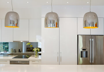 Modern Kitchen with mirrored splashback and metal light pendents