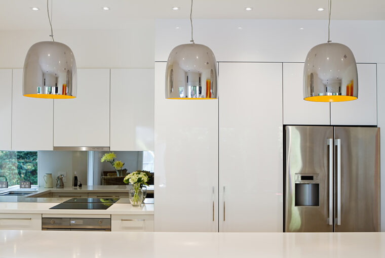 Modern Kitchen with mirrored splashback and metal light pendents