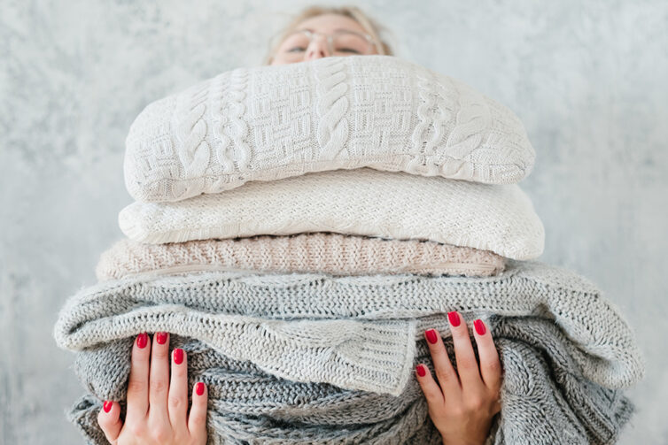 Women carying a pile of warm winter blankets