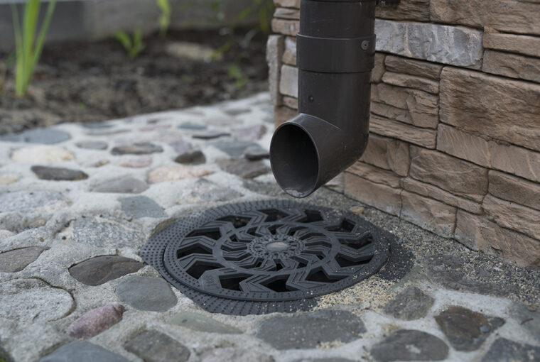 Dark coloured drain pipe leading to drain cover fitted into the ground