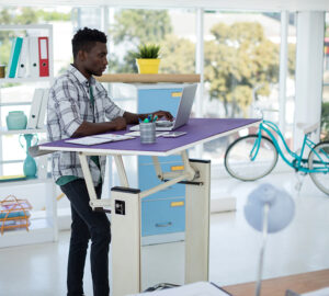 Man working at a purple standing desk. Ergonomic Home Office