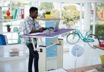 Man working at a purple standing desk. Ergonomic Home Office