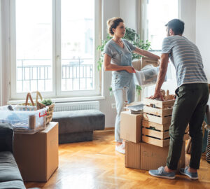 Women and man standing by window with boxes from house move