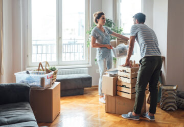 Women and man standing by window with boxes from house move