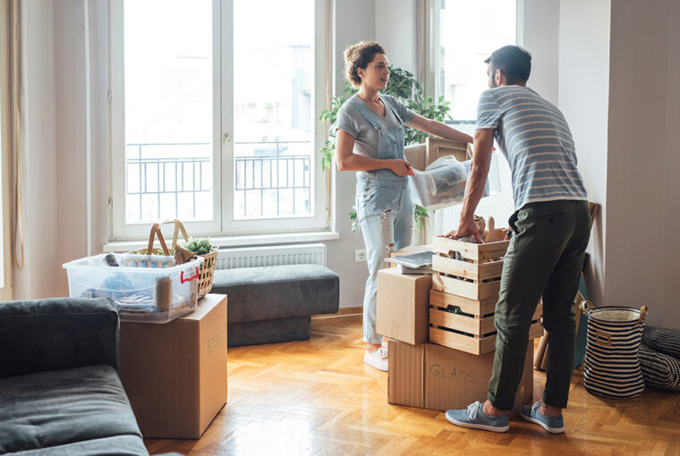 Women and man standing by window with boxes from house move