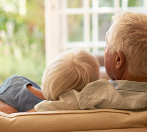 Elderly couple sat next to each other and hugging each other