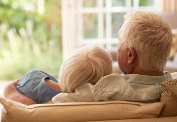 Elderly couple sat next to each other and hugging each other