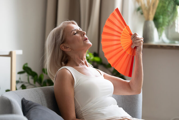 Women using red paper hand fan to cool down