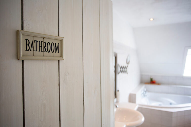Bathroom with corner bath and basin. Door with bathroom sign