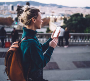 Women walking along spanish street with backpack and mobile phone