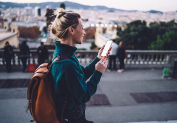 Women walking along spanish street with backpack and mobile phone