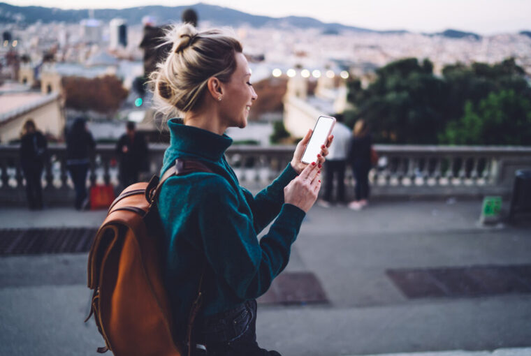 Women walking along spanish street with backpack and mobile phone