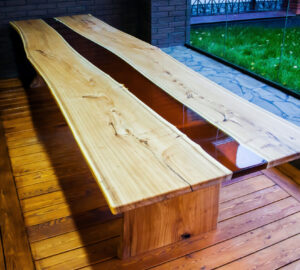 Large long wooden table with epoxy design in the middle. Placed in room with large floor to ceiling window