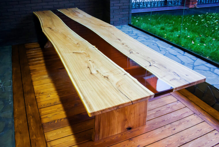 Large long wooden table with epoxy design in the middle. Placed in room with large floor to ceiling window