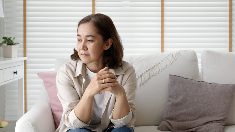 Women sat on white sofa looking lost in thought
