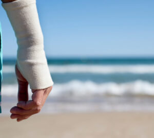 Man on holiday at the beach with right wrist bandaged