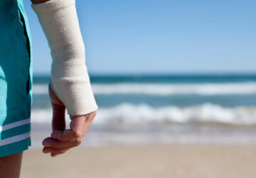 Man on holiday at the beach with right wrist bandaged