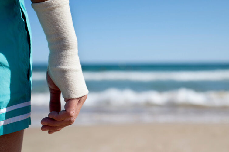 Man on holiday at the beach with right wrist bandaged