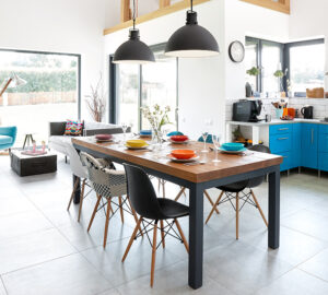 Morden kitchen including blue modern kitchen units, grey tiled floor and large black and wood kitchen table and chairs