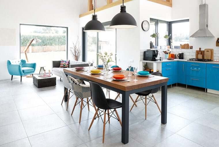 Morden kitchen including blue modern kitchen units, grey tiled floor and large black and wood kitchen table and chairs