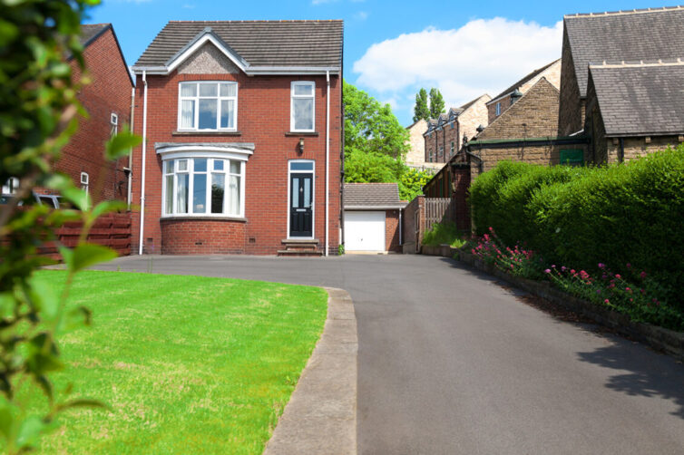 Small detached house made of red bricks with long driveway