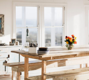 Large rustic wooden dining table and bench in white rustic room