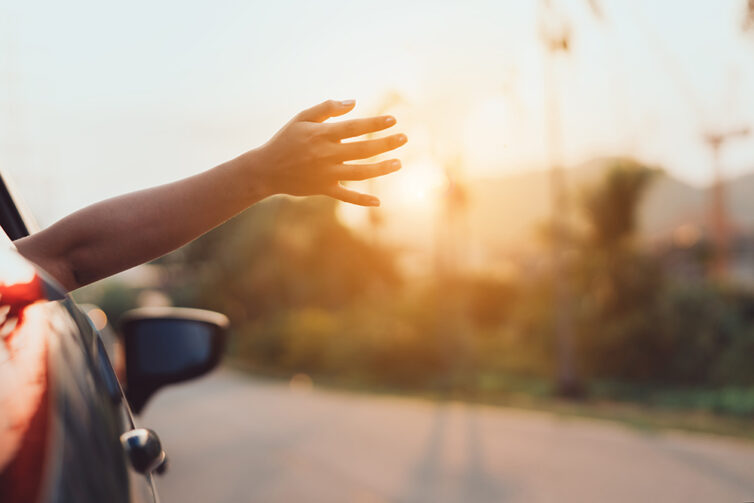 persons arm and hand hanging out of the car window whilst driving along