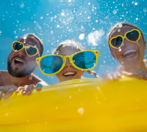 Family having fun on holiday in the pool with yellow inflatable and yellow sun glasses