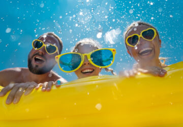 Family having fun on holiday in the pool with yellow inflatable and yellow sun glasses