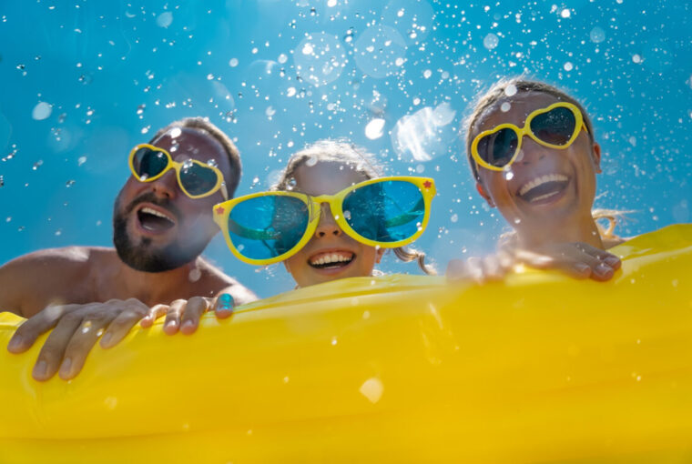 Family having fun on holiday in the pool with yellow inflatable and yellow sun glasses