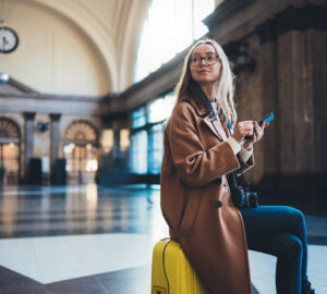 Women sat on yellow luggage waiting at Barcelona train station