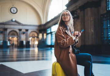 Women sat on yellow luggage waiting at Barcelona train station