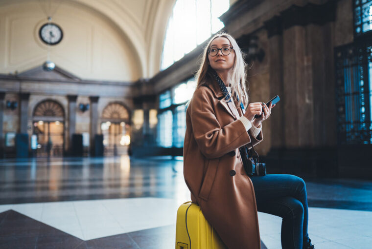 Women sat on yellow luggage waiting at Barcelona train station