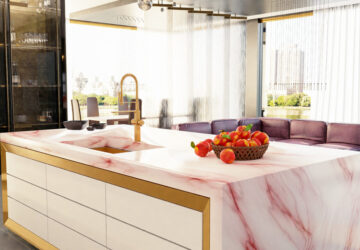 Modern designer kitchen with pink marble island counter top, with metal/brass draw triming and brass taps