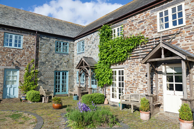 Two country cottages in cornwall - semi detached. One cottage with white window frames the other cottage with blue window frames