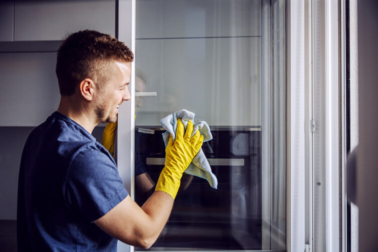 Man with yellow gloves on cleaning windows