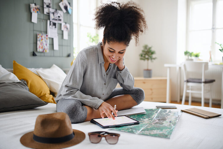 Young women planing holiday, sat with map, hat, sunglasses and ipad