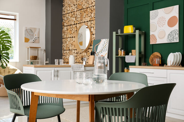 Kitchen with green painted walls, green dining chairs and feature log wall in livingroom