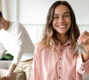 Male and female moving into new property. Women holding keys, man opening boxes