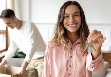 Male and female moving into new property. Women holding keys, man opening boxes