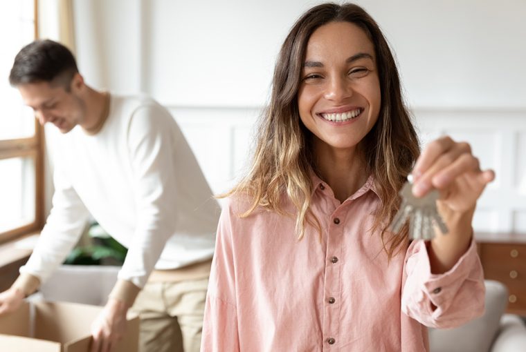 Male and female moving into new property. Women holding keys, man opening boxes