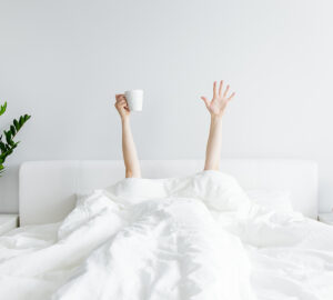 Person under white duvet with arms reaching out