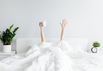 Person under white duvet with arms reaching out