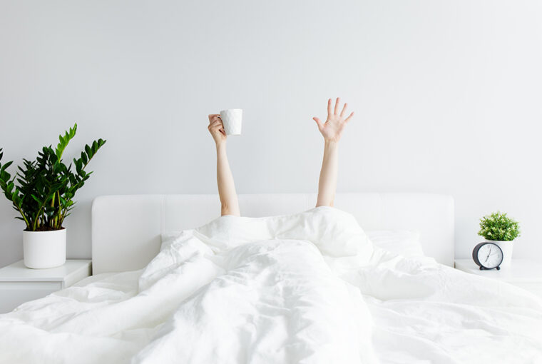 Person under white duvet with arms reaching out