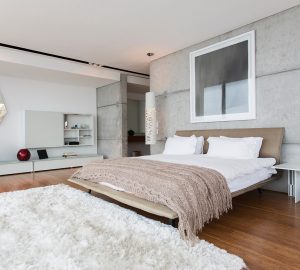 Large modern bedroom with wooden floor and large white fluffy rug