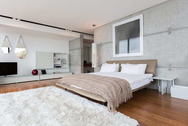 Large modern bedroom with wooden floor and large white fluffy rug