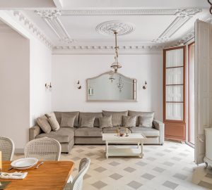 Classic living room with ceiling coving. Furniture including dining table and big sofa. Tiled flooring and large wooden double door.