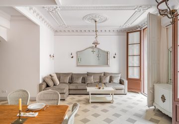 Classic living room with ceiling coving. Furniture including dining table and big sofa. Tiled flooring and large wooden double door.