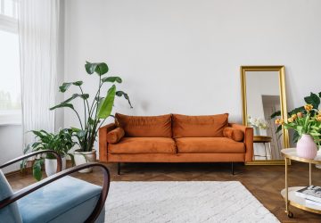 Retro looking sofa in orangy brown. Large plant wooden floors and large white rug